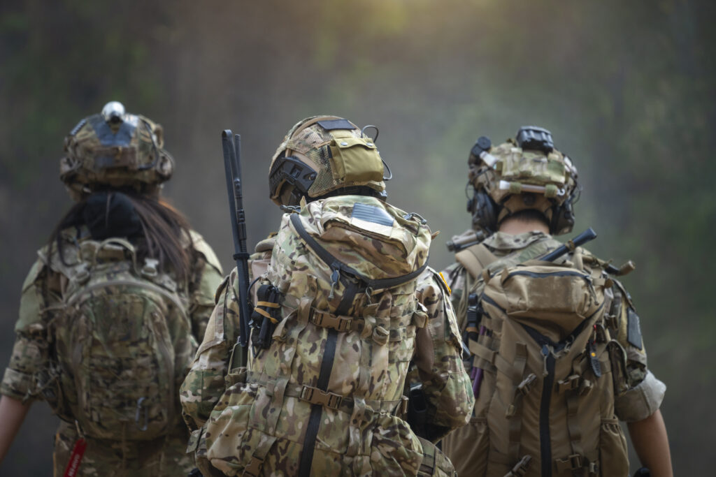 Rear Of Soldiers Patrolling Along The Risky Area.